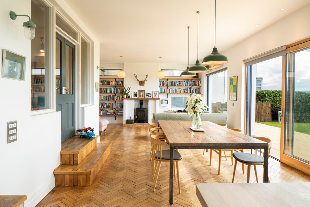 Foto på ett mellanstort funkis kök med matplats, med vita väggar, en öppen vedspis, en spiselkrans i tegelsten och brunt golv