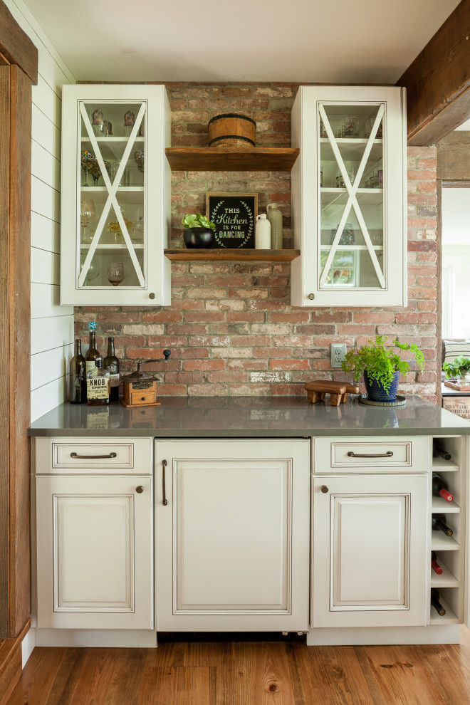 Design ideas for a mid-sized country u-shaped home bar in Seattle with an undermount sink, raised-panel cabinets, white cabinets, quartz benchtops, white splashback, shiplap splashback, medium hardwood floors, brown floor and grey benchtop.