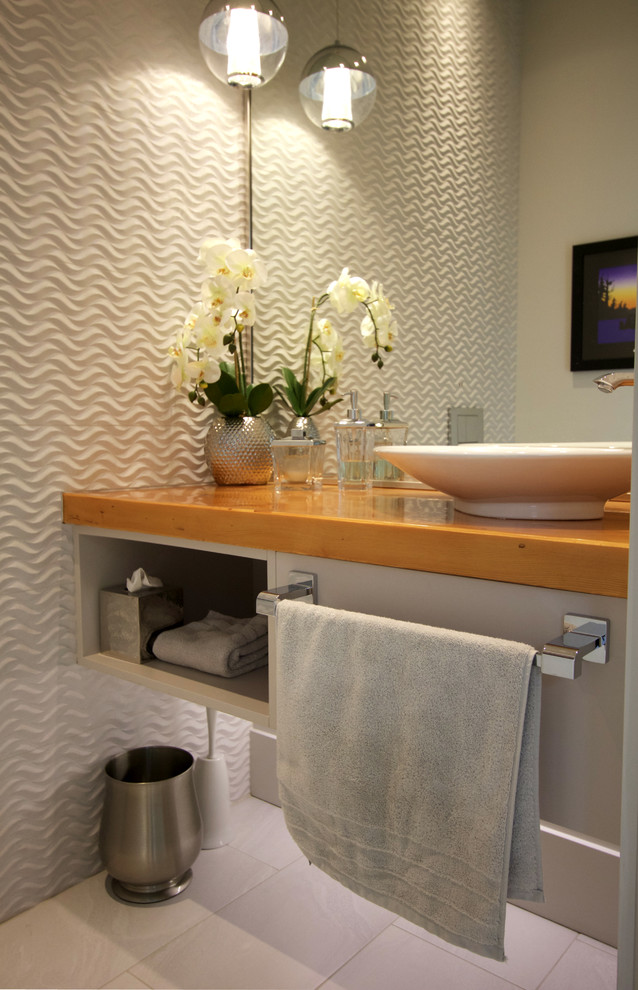 This is an example of a small modern powder room in Vancouver with open cabinets, grey cabinets, gray tile, porcelain floors, a vessel sink, wood benchtops, white floor and brown benchtops.