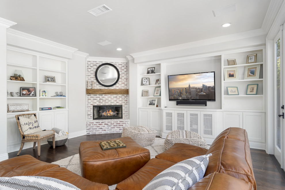 Inspiration for a large beach style open concept family room in Orange County with a home bar, white walls, dark hardwood floors, a corner fireplace, a brick fireplace surround, a wall-mounted tv and brown floor.