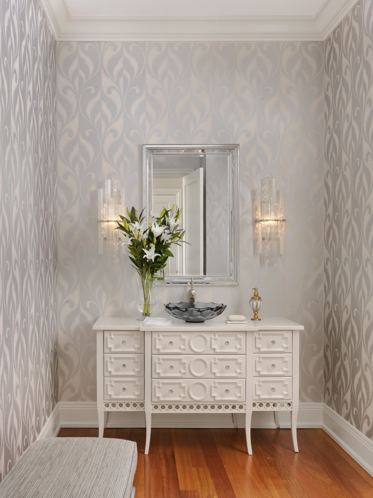 Design ideas for a traditional powder room in Other with beaded inset cabinets, white cabinets, multi-coloured walls, medium hardwood floors, a vessel sink, wood benchtops, brown floor, white benchtops, a freestanding vanity and wallpaper.