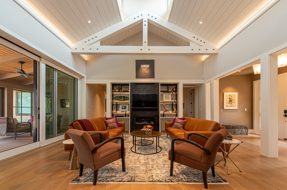 Example of a huge farmhouse open concept light wood floor, yellow floor and exposed beam living room design in San Francisco with a bar, gray walls, a metal fireplace and a media wall
