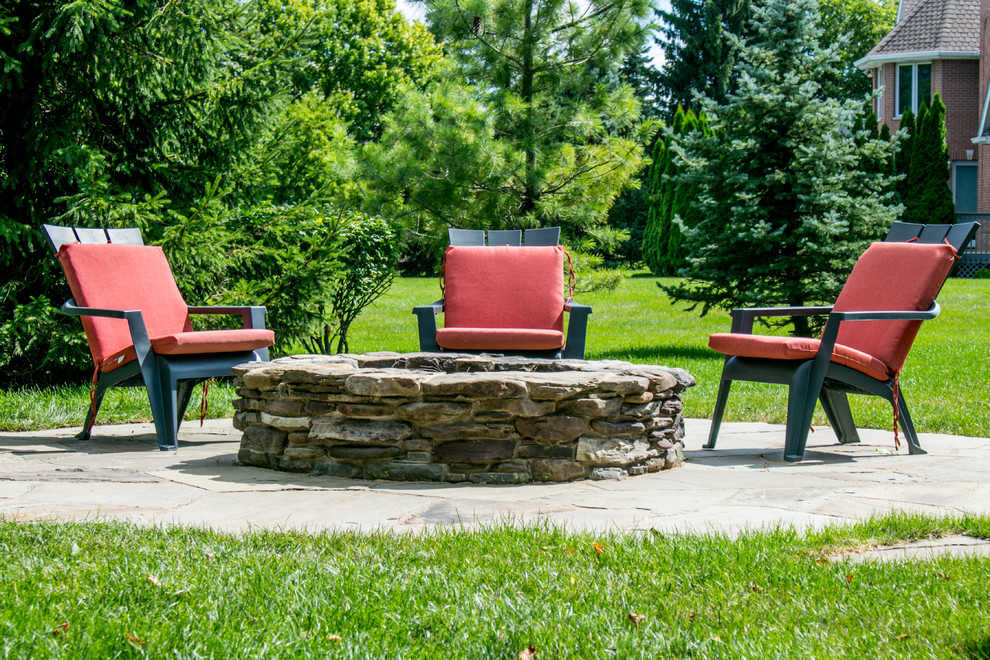 Design ideas for a rustic backyard stone landscaping in Chicago with a fire pit.