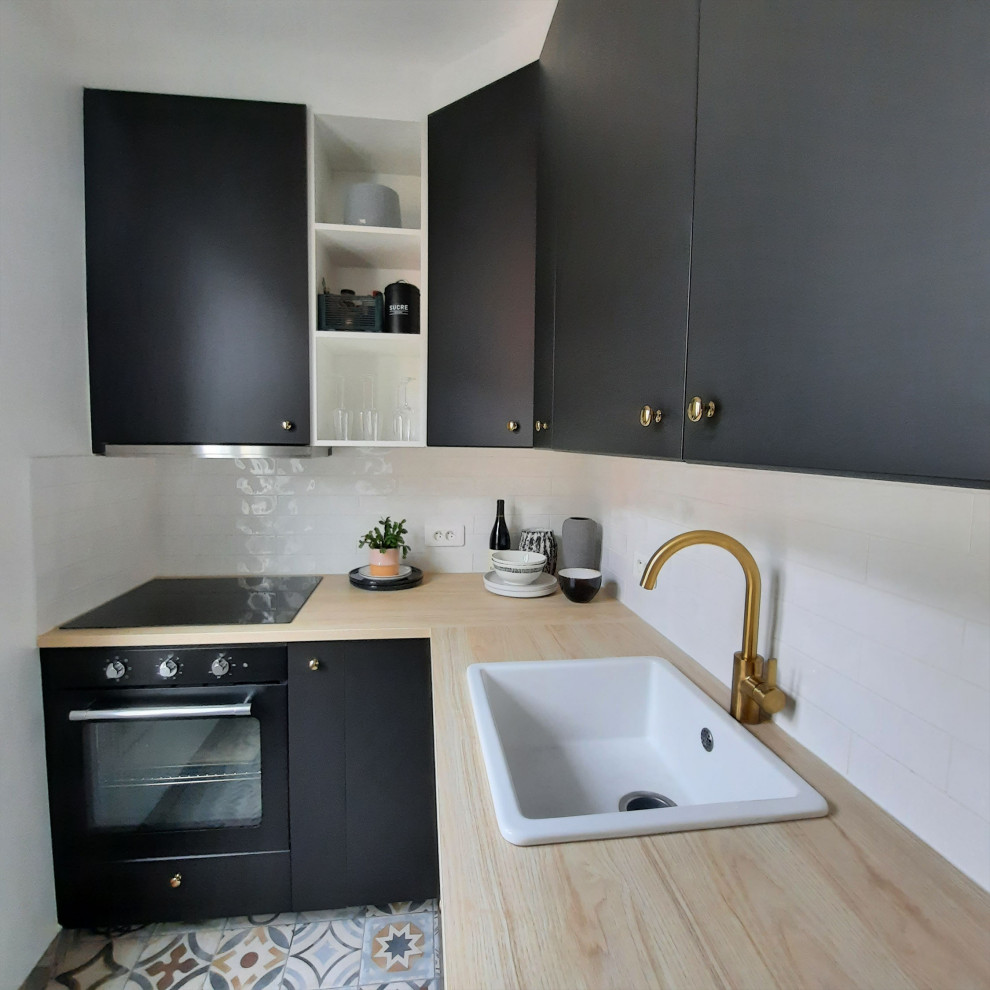 Bild på ett avskilt, mellanstort funkis beige beige l-kök, med en rustik diskho, luckor med profilerade fronter, svarta skåp, laminatbänkskiva, vitt stänkskydd, stänkskydd i stickkakel, svarta vitvaror, cementgolv och grått golv