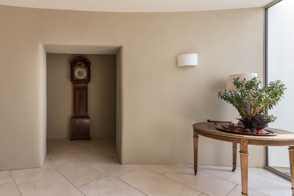 Aménagement d'un grand couloir contemporain avec un mur beige, un sol en calcaire et un sol beige.