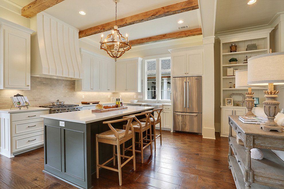 Inspiration for a large transitional l-shaped open plan kitchen in New Orleans with a farmhouse sink, recessed-panel cabinets, white cabinets, white splashback, subway tile splashback, stainless steel appliances, medium hardwood floors and with island.
