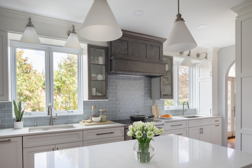 Inspiration for a mid-sized transitional l-shaped medium tone wood floor and brown floor enclosed kitchen remodel with an undermount sink, shaker cabinets, white cabinets, quartz countertops, blue backsplash, subway tile backsplash, stainless steel appliances, an island and white countertops
