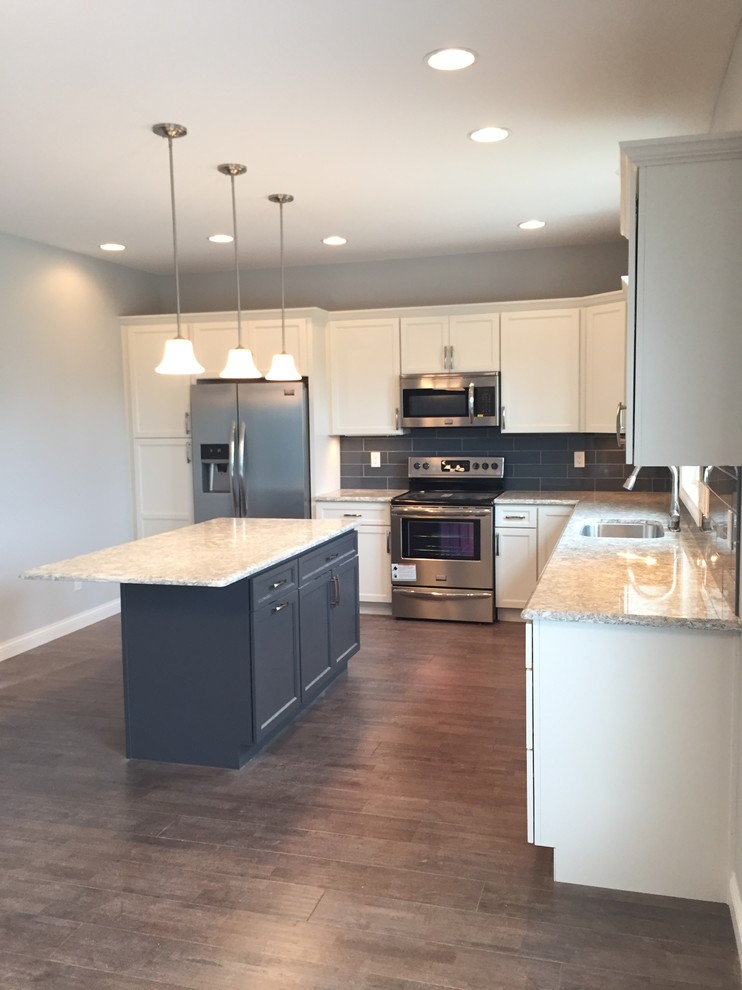 Open concept kitchen - large transitional l-shaped open concept kitchen idea with an undermount sink, raised-panel cabinets, white cabinets, quartz countertops, gray backsplash, stainless steel appliances and an island