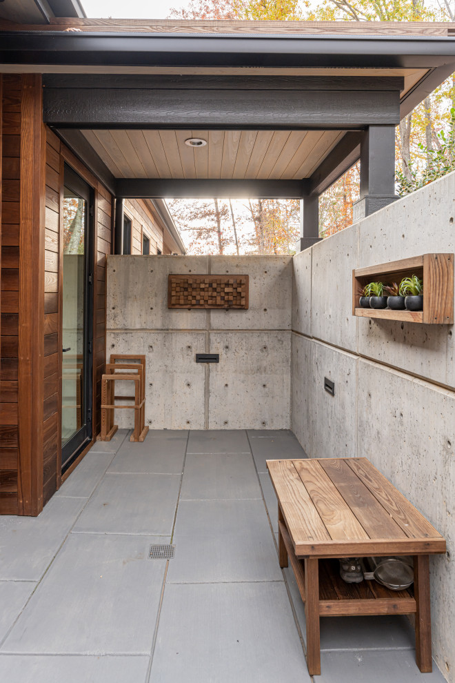 Ispirazione per un piccolo patio o portico moderno nel cortile laterale con cemento stampato e un tetto a sbalzo