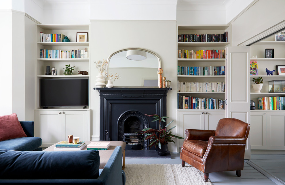 Mittelgroßes, Offenes Klassisches Wohnzimmer mit beiger Wandfarbe, gebeiztem Holzboden, Kamin, Kaminumrandung aus Metall, freistehendem TV und grauem Boden in London