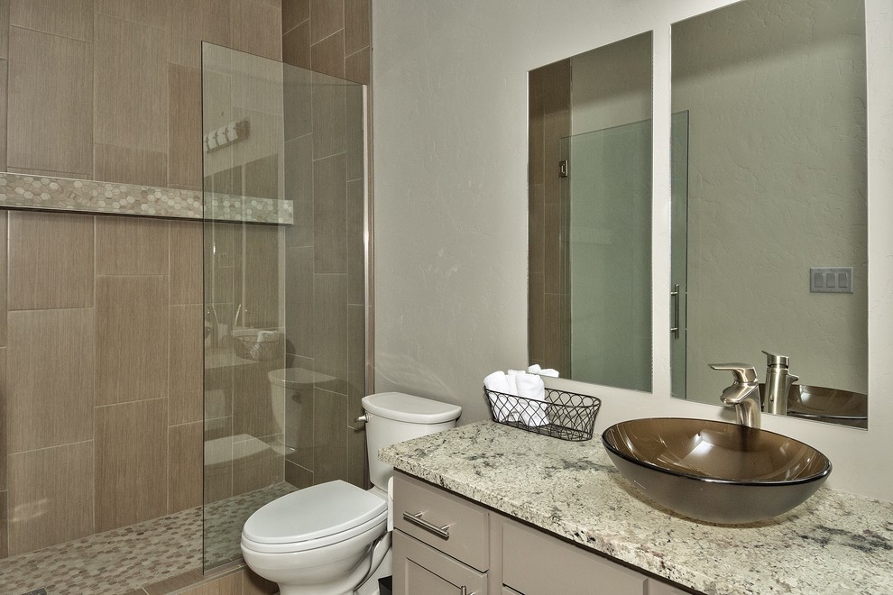 Example of a mid-sized transitional 3/4 brown tile and porcelain tile alcove shower design in Denver with recessed-panel cabinets, beige cabinets, a two-piece toilet, white walls, a vessel sink and granite countertops