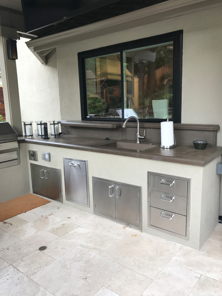 Backyard kitchen with overhead structure, raised garden and stone pavers