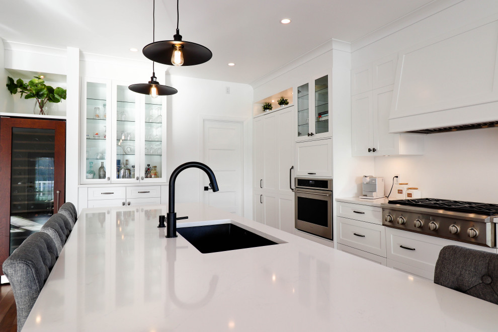 Large transitional l-shaped medium tone wood floor and brown floor open concept kitchen photo with an undermount sink, shaker cabinets, white cabinets, quartzite countertops, white backsplash, ceramic backsplash, stainless steel appliances and an island