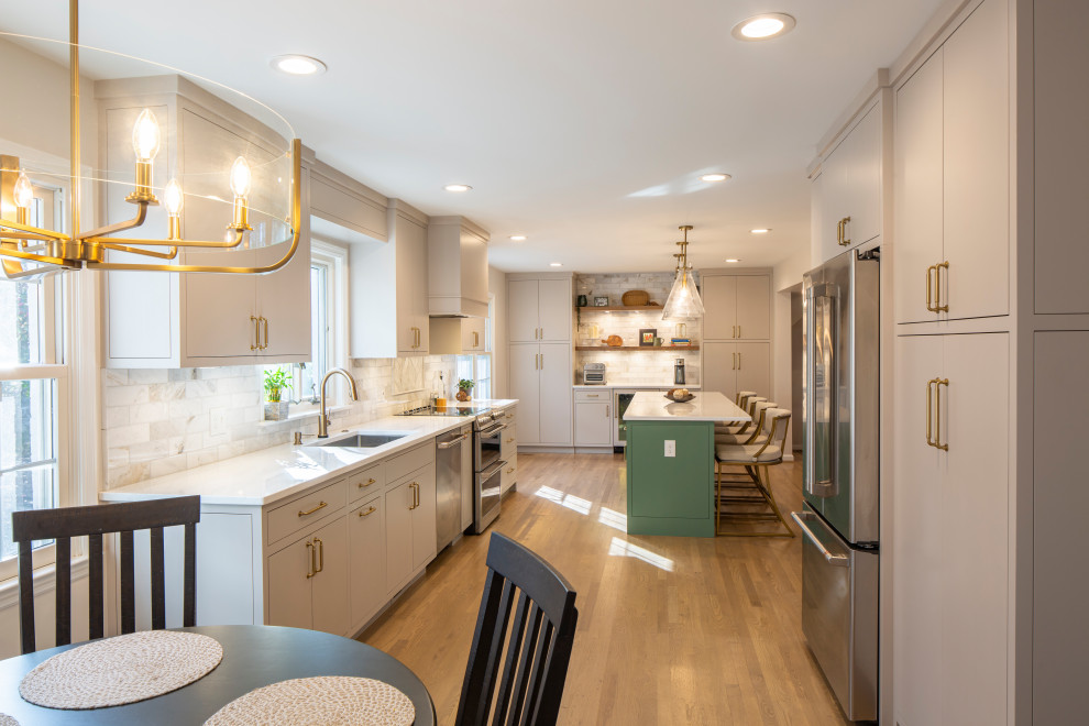 Example of a mid-sized transitional l-shaped medium tone wood floor eat-in kitchen design in Cincinnati with an undermount sink, beige cabinets, quartz countertops, marble backsplash, stainless steel appliances, an island and white countertops