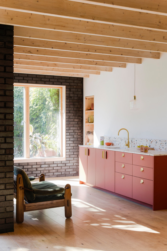 Design ideas for a small mediterranean single-wall open plan kitchen in Gloucestershire with a single-bowl sink, flat-panel cabinets, pink cabinets, terrazzo benchtops, multi-coloured splashback, marble splashback, light hardwood floors, no island and multi-coloured benchtop.