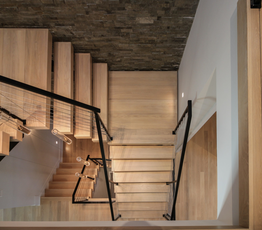 Design ideas for a large eclectic wood floating metal railing staircase in DC Metro with brick walls.