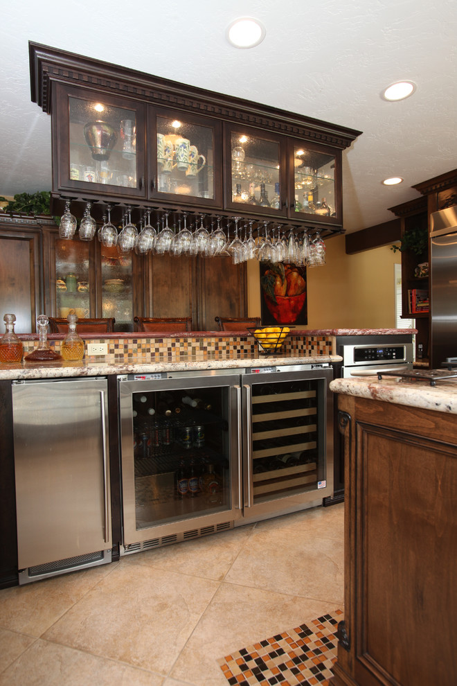Photo of a mid-sized mediterranean wet bar in Los Angeles with glass-front cabinets, dark wood cabinets, granite benchtops, multi-coloured splashback, mosaic tile splashback, ceramic floors and beige floor.
