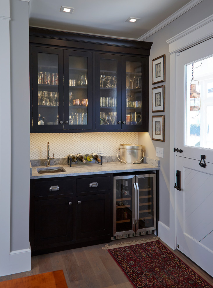 Inspiration for a mid-sized transitional single-wall wet bar in Providence with an undermount sink, shaker cabinets, black cabinets, marble benchtops, white splashback, marble splashback, medium hardwood floors, grey floor and grey benchtop.