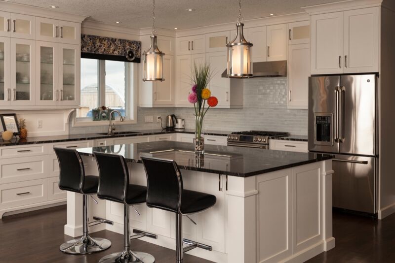 Transitional l-shaped dark wood floor open concept kitchen photo in Toronto with an undermount sink, shaker cabinets, white cabinets, marble countertops, blue backsplash, glass tile backsplash, stainless steel appliances and an island