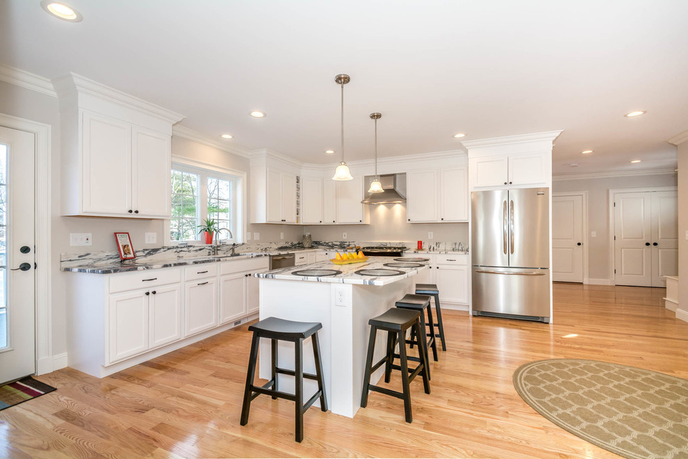 Inspiration for a large transitional l-shaped brown floor and medium tone wood floor eat-in kitchen remodel in Boston with an undermount sink, recessed-panel cabinets, white cabinets, stone slab backsplash, stainless steel appliances, an island and quartzite countertops