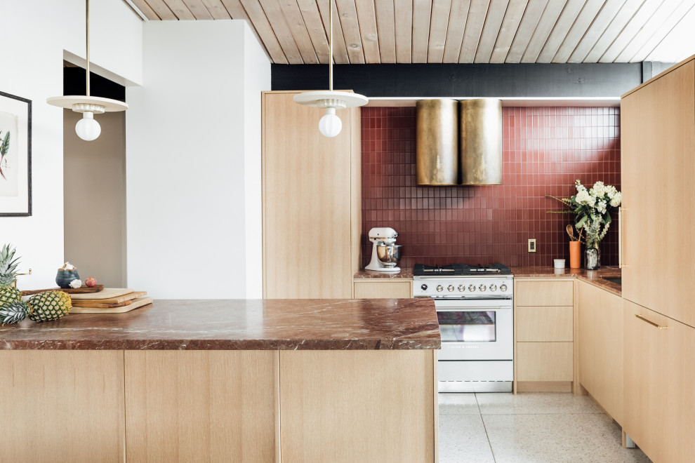 Photo of a mid-sized midcentury l-shaped eat-in kitchen in Salt Lake City with an integrated sink, flat-panel cabinets, light wood cabinets, marble benchtops, red splashback, glass tile splashback, white appliances, terrazzo floors, a peninsula, grey floor, red benchtop and exposed beam.