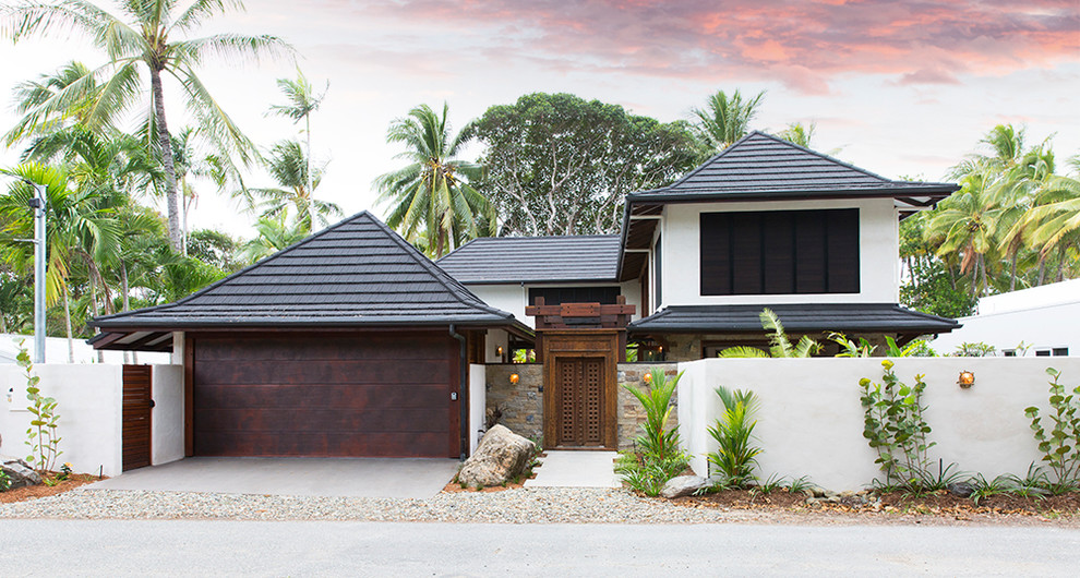 Photo of a tropical two-storey white house exterior in Cairns with a hip roof and a shingle roof.
