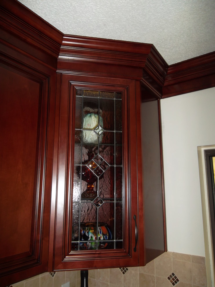 Inspiration for a mid-sized transitional l-shaped ceramic tile kitchen remodel with a drop-in sink, dark wood cabinets, granite countertops, stone tile backsplash, stainless steel appliances, an island and raised-panel cabinets