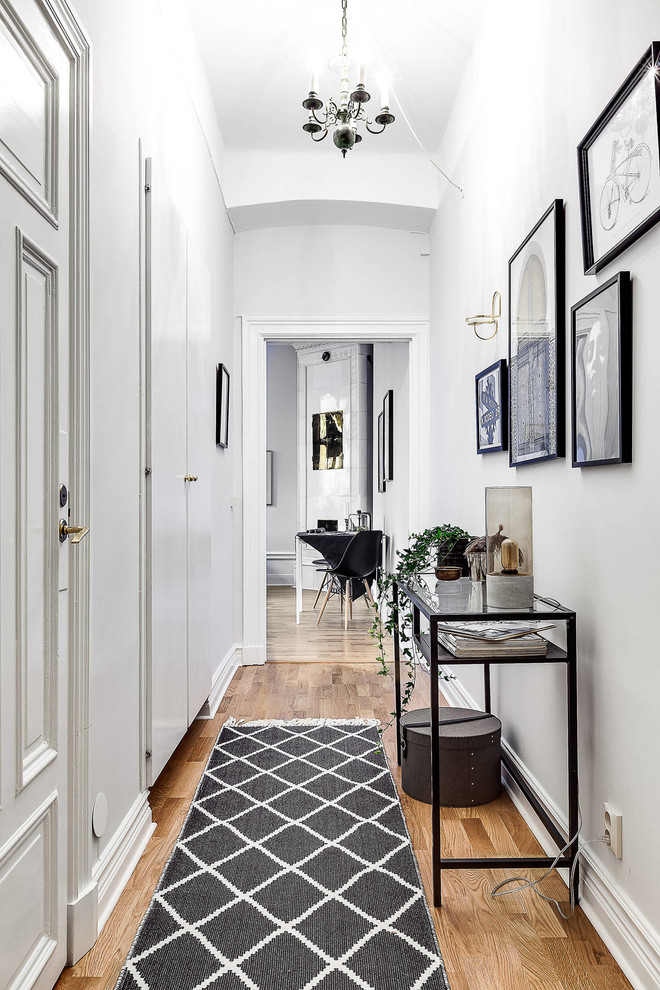 Inspiration for a scandinavian hallway in Stockholm with white walls, medium hardwood floors and brown floor.