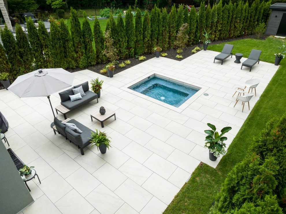 Imagen de piscinas y jacuzzis actuales pequeños rectangulares en patio trasero con adoquines de piedra natural