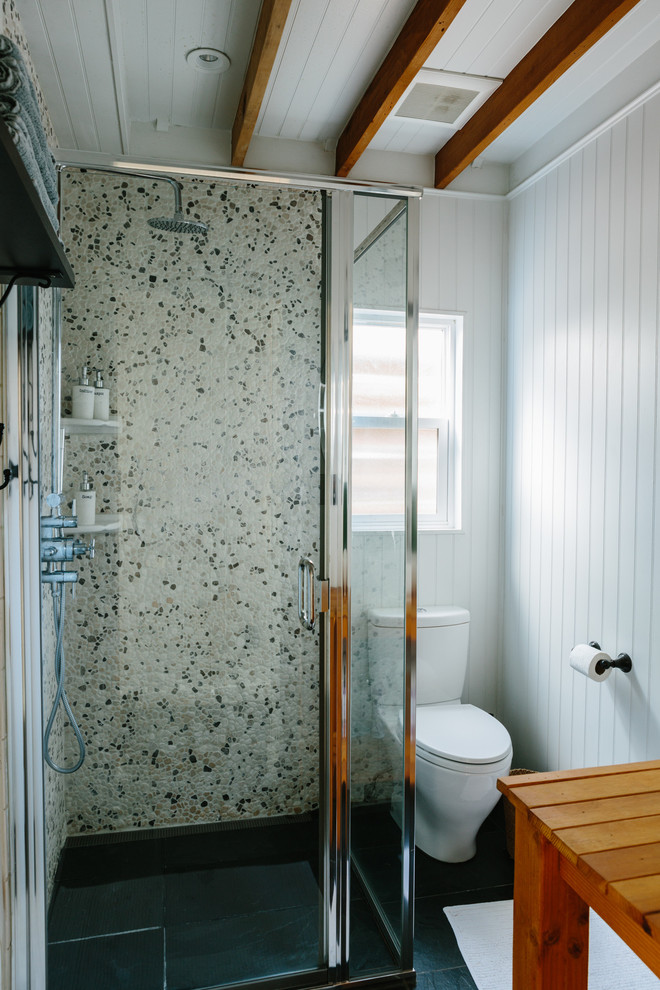 This is an example of a small transitional bathroom in Other with open cabinets, medium wood cabinets, a corner shower, a one-piece toilet, multi-coloured tile, stone tile, white walls, slate floors, a pedestal sink, wood benchtops, black floor and a hinged shower door.