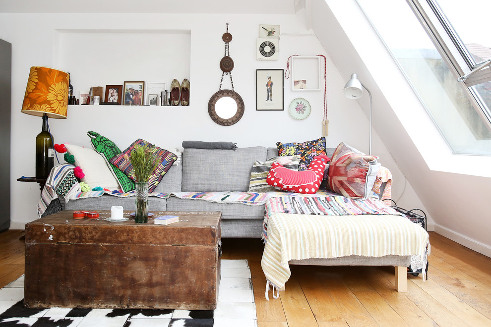 This is an example of an eclectic living room in London with white walls and light hardwood floors.