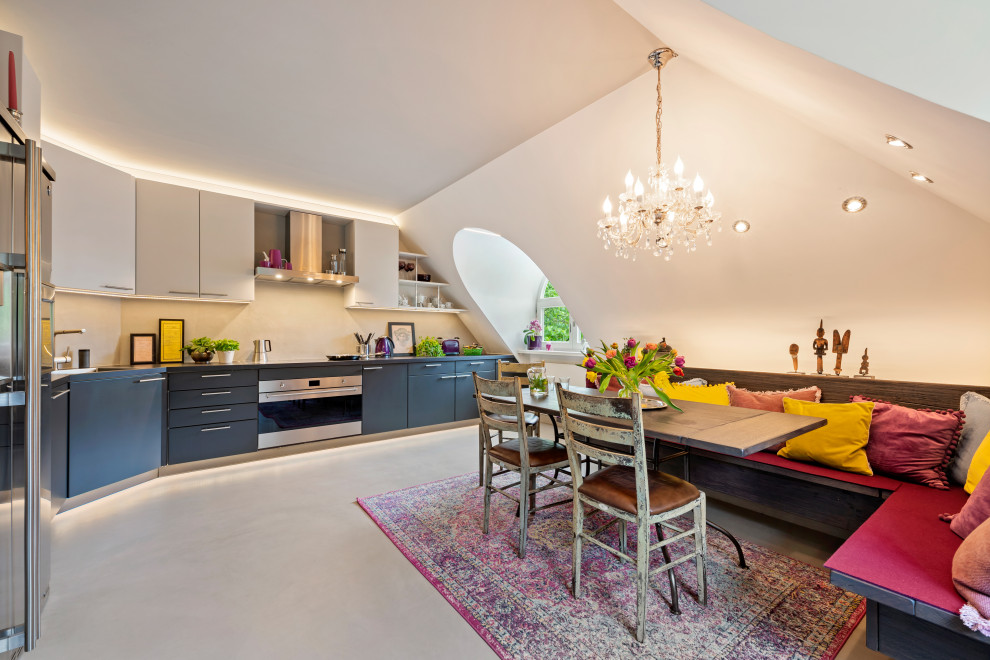 Large contemporary l-shaped eat-in kitchen in Munich with flat-panel cabinets, solid surface benchtops, beige splashback, black benchtop, grey cabinets, concrete floors, no island, grey floor and vaulted.
