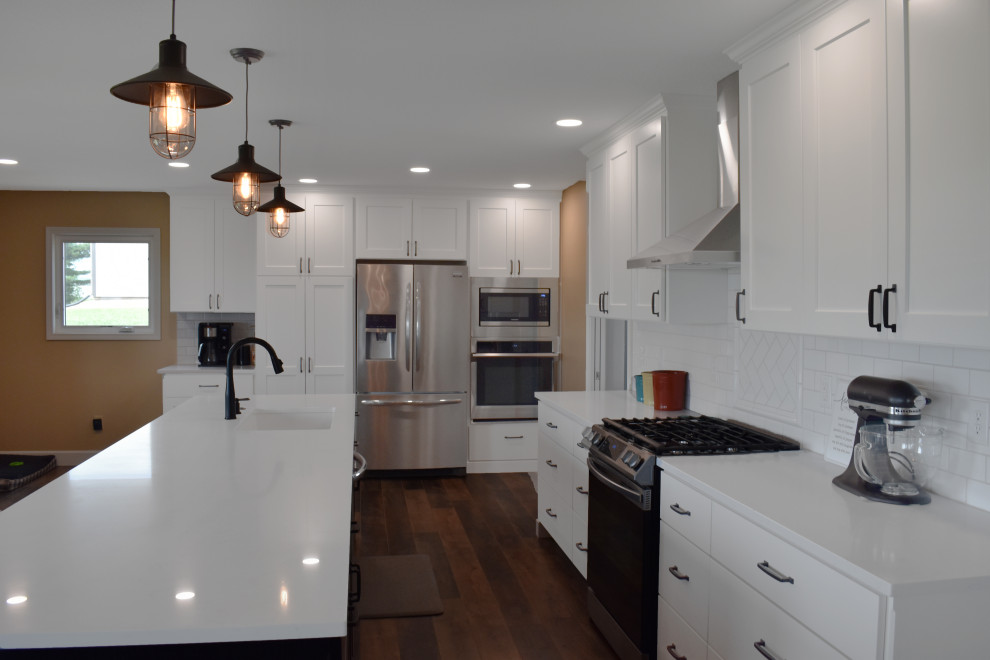 Open concept kitchen - large modern l-shaped vinyl floor and brown floor open concept kitchen idea with a drop-in sink, yellow cabinets, quartzite countertops, yellow backsplash, subway tile backsplash, stainless steel appliances, an island and white countertops