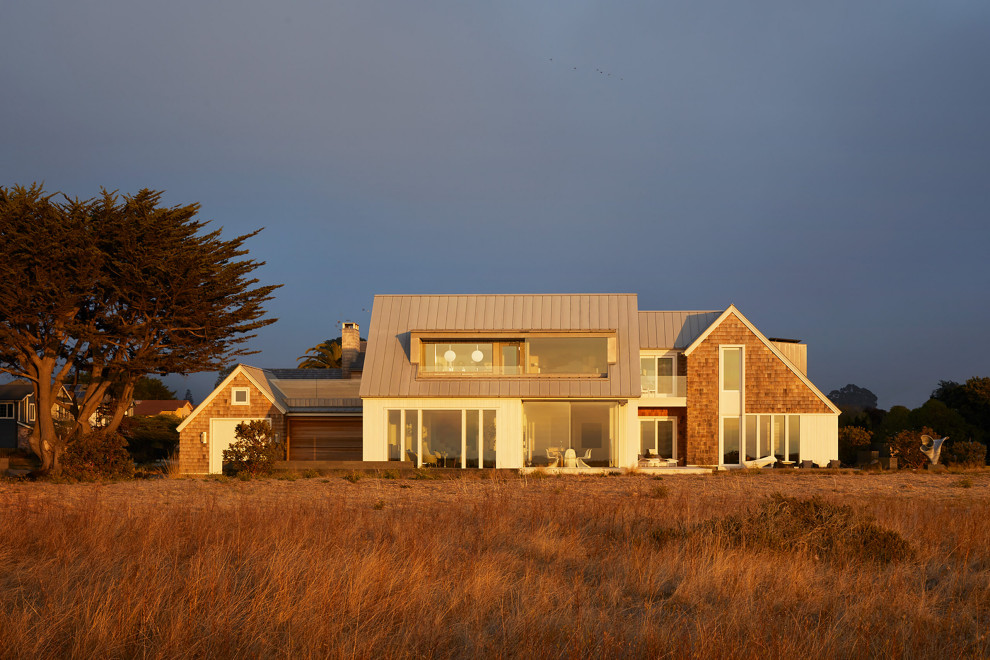 This is an example of a beach style white house exterior in San Francisco with mixed siding, a grey roof and shingle siding.
