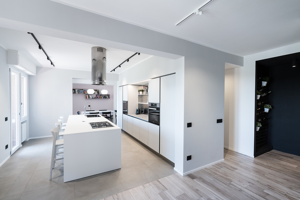 This is an example of a large contemporary galley kitchen in Rome with flat-panel cabinets, white cabinets, stainless steel appliances, with island, grey floor, white benchtop and a drop-in sink.