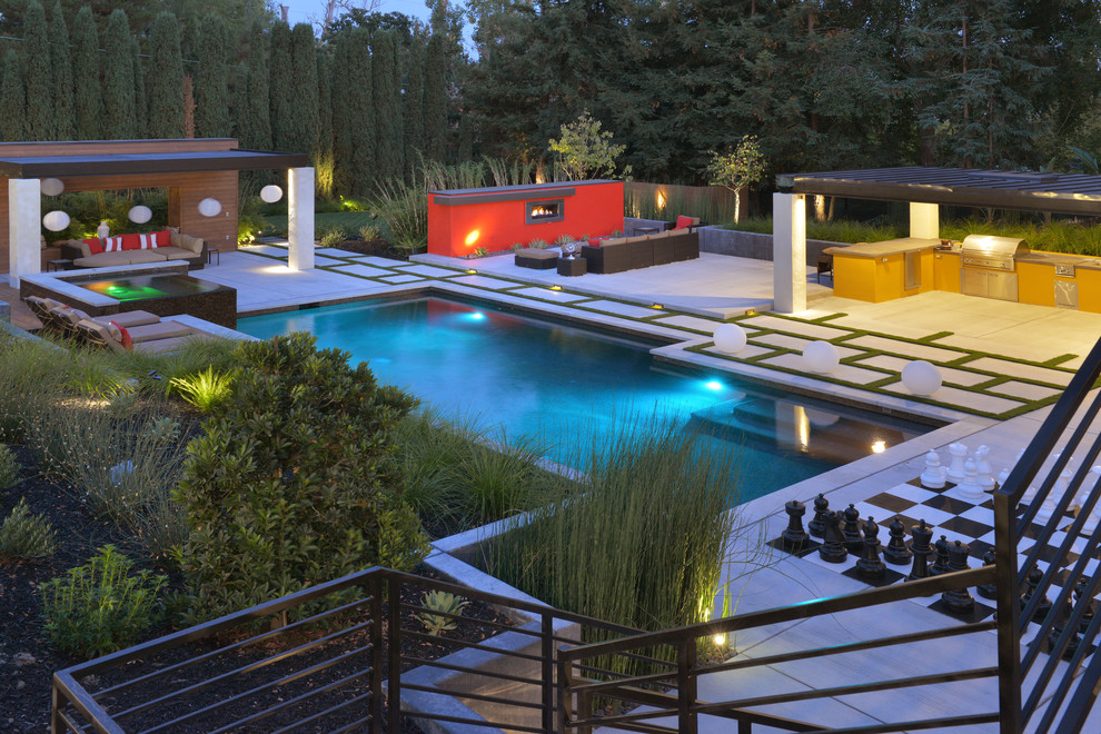 This is an example of an expansive contemporary backyard custom-shaped lap pool in San Francisco with a hot tub and concrete pavers.
