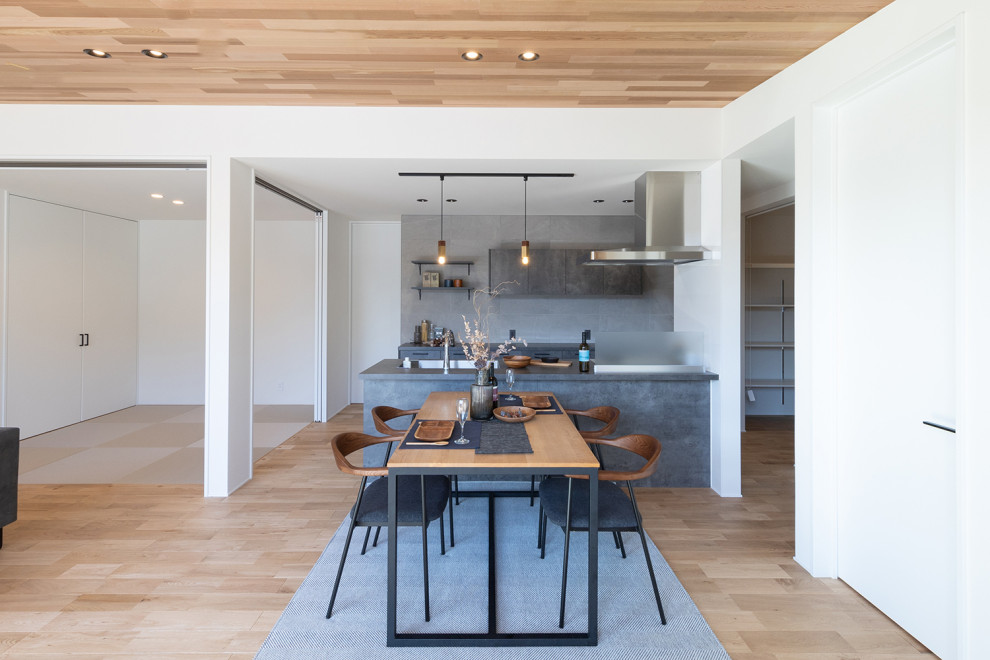 This is an example of a world-inspired open plan dining room in Other with white walls, medium hardwood flooring, no fireplace, brown floors, a wood ceiling, wallpapered walls and feature lighting.