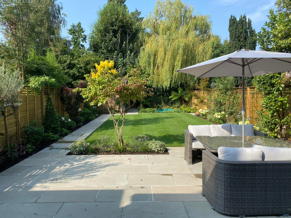 Immagine di un grande giardino formale minimal esposto in pieno sole dietro casa in estate con pavimentazioni in pietra naturale e recinzione in legno