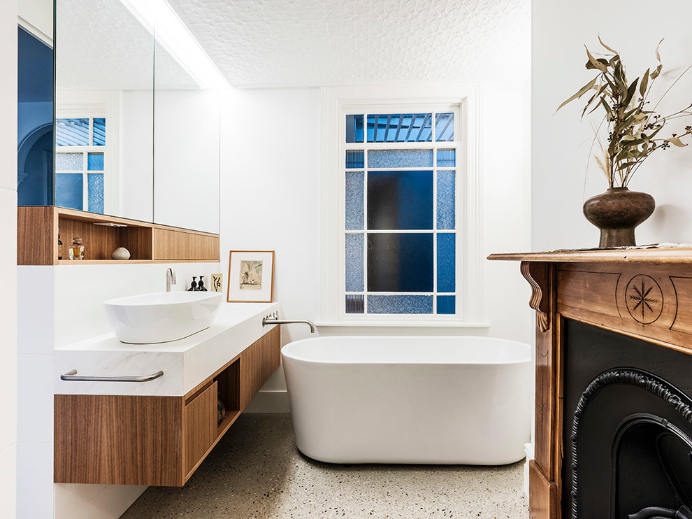 Photo of a mid-sized contemporary master bathroom in Sydney with medium wood cabinets, a freestanding tub, white walls, concrete floors, a vessel sink, beige floor, white benchtops, an alcove shower, a one-piece toilet, white tile, ceramic tile, engineered quartz benchtops, an open shower and flat-panel cabinets.
