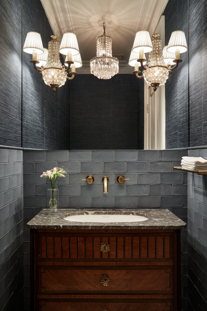 Design ideas for a small transitional powder room in Other with furniture-like cabinets, medium wood cabinets, a wall-mount toilet, blue tile, subway tile, blue walls, marble floors, an undermount sink, marble benchtops, grey floor, grey benchtops, a freestanding vanity and wallpaper.