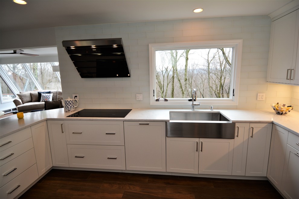 Large contemporary u-shaped eat-in kitchen in New York with an undermount sink, shaker cabinets, white cabinets, quartz benchtops, white splashback, cement tile splashback, black appliances, a peninsula, ceramic floors and brown floor.