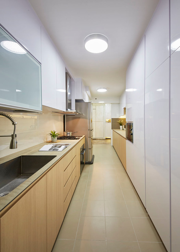 This is an example of a mid-sized modern galley kitchen pantry in Singapore with a single-bowl sink, flat-panel cabinets, medium wood cabinets, wood benchtops, beige splashback, ceramic splashback, stainless steel appliances and ceramic floors.