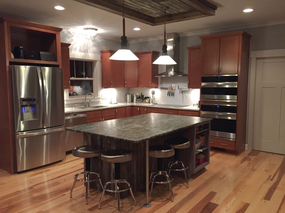 Photo of a mid-sized eclectic l-shaped eat-in kitchen in Indianapolis with an undermount sink, shaker cabinets, medium wood cabinets, granite benchtops, stainless steel appliances, light hardwood floors and with island.