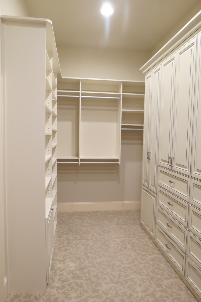 Photo of a large traditional women's walk-in wardrobe in Atlanta with distressed cabinets, carpet, recessed-panel cabinets and beige floor.
