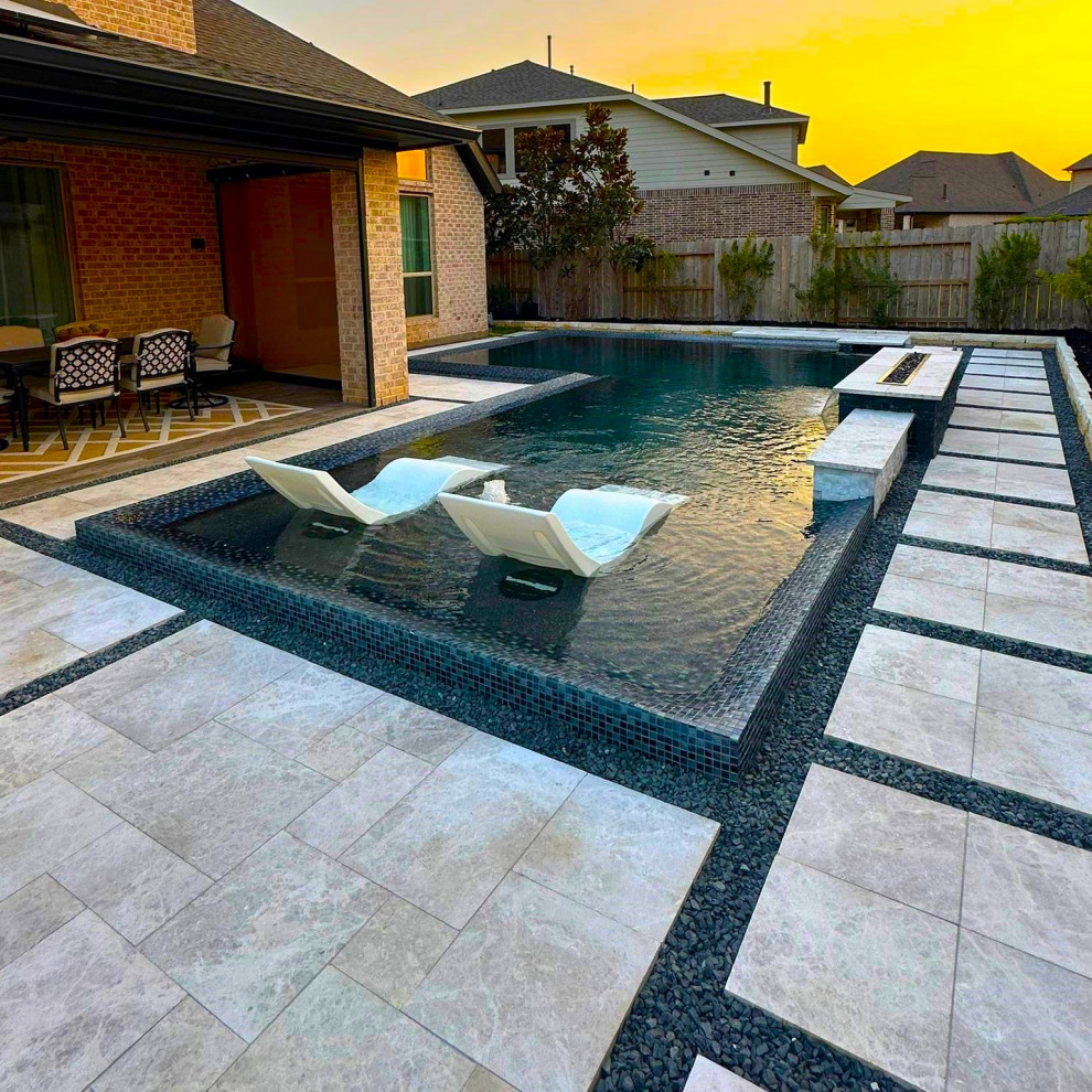 Immagine di una piscina moderna a "L" con pavimentazioni in pietra naturale