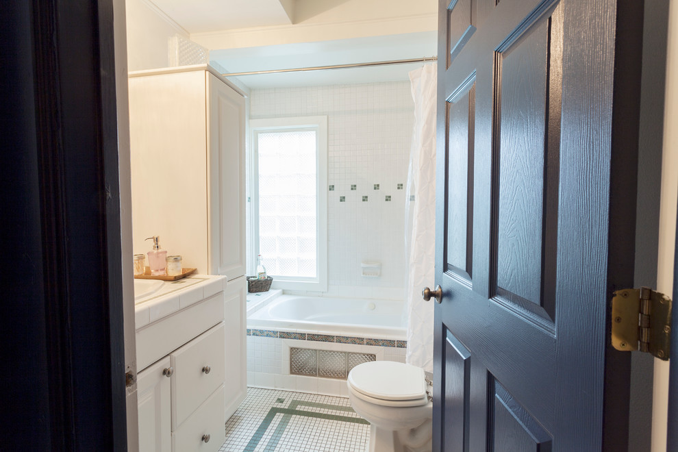 Photo of a small eclectic 3/4 bathroom in Nashville with raised-panel cabinets, white cabinets, an alcove tub, a shower/bathtub combo, a two-piece toilet, white tile, mosaic tile, white walls, mosaic tile floors, a drop-in sink and tile benchtops.