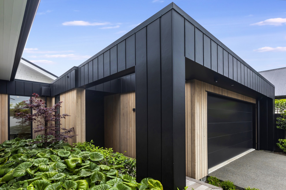 This is an example of a mid-sized contemporary attached two-car garage in Christchurch.