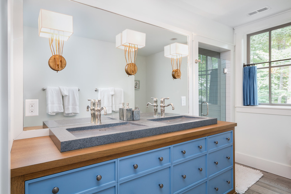 This is an example of a mid-sized transitional 3/4 bathroom in Charlotte with recessed-panel cabinets, blue cabinets, white walls, wood benchtops and a hinged shower door.