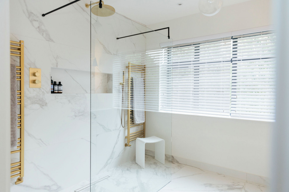 Large transitional master bathroom in London with flat-panel cabinets, blue cabinets, an open shower, a wall-mount toilet, white tile, marble, white walls, marble floors, a drop-in sink, marble benchtops, white floor, an open shower, white benchtops, a double vanity, a built-in vanity and brick walls.