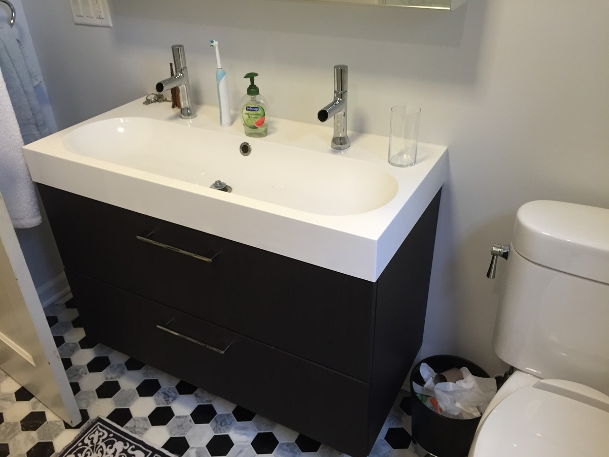 This is an example of a small contemporary bathroom in New York with shaker cabinets, black cabinets, a drop-in tub, a shower/bathtub combo, a one-piece toilet, gray tile, marble, grey walls, ceramic floors, an integrated sink, quartzite benchtops, multi-coloured floor and a hinged shower door.